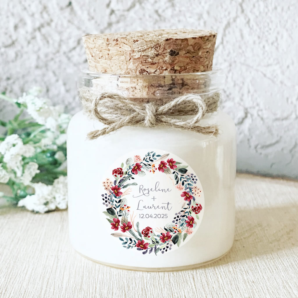 Bougie personnalisée mariage décorée d’une couronne florale rouge et de feuillage eucalyptus.